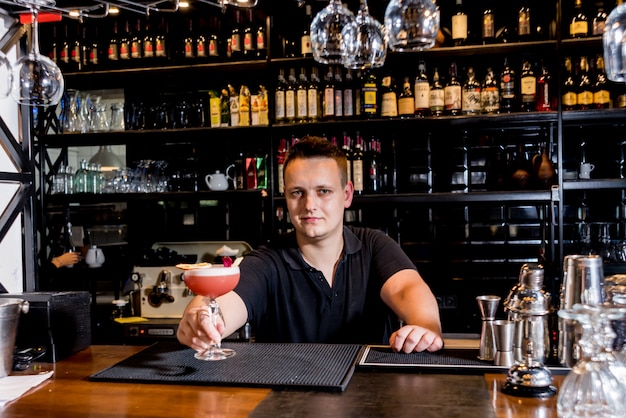 Barman está fazendo um coquetel no balcão do bar. Coquetéis frescos.