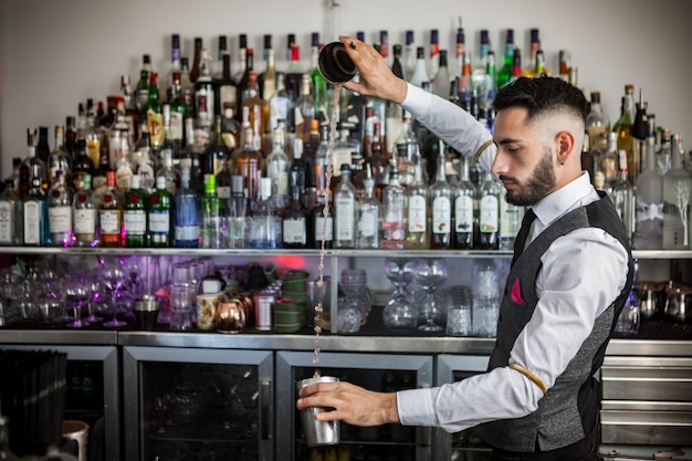 Barman experto con coctelera preparando cócteles