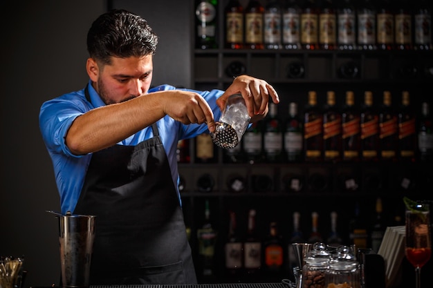 El barman experto está haciendo un cóctel.