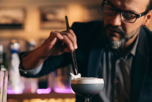 Barman experto está haciendo cócteles en el club nocturno.