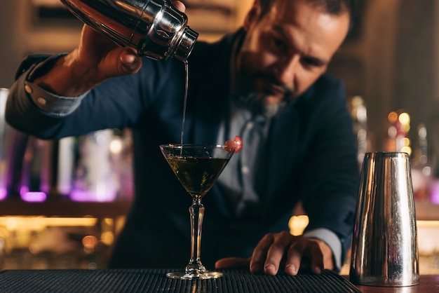 Barman experto está haciendo cócteles en el club nocturno.