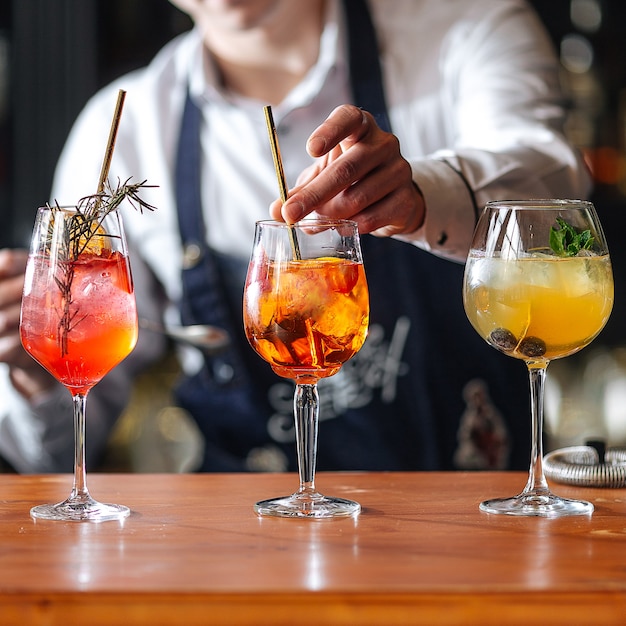 Barman fazendo cocktailes com álcool de frutas na mesa de madeira