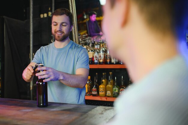 Foto barman flasche bier in der nähe leeres glas auf holztheke im inneren des pubs beschnittener freiraum