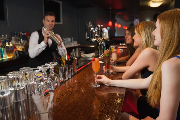 Barman guapo haciendo cócteles para mujeres atractivas