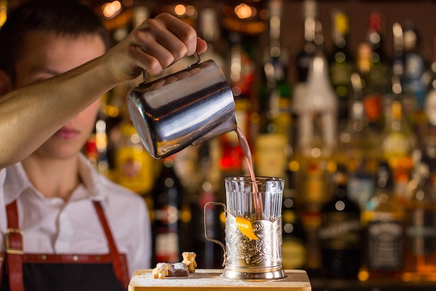 El barman haciendo cócteles en un bar de discoteca. Verter el cóctel en un vaso.