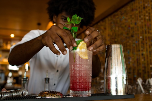 Barman latino a colocar uma tampa de hortelã no coquetel.