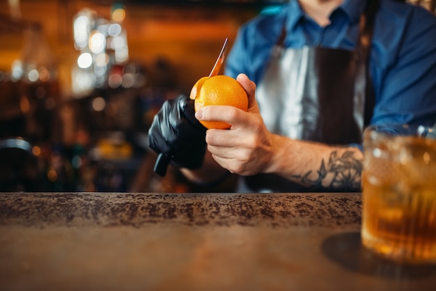 Barman limpa laranja no balcão do bar