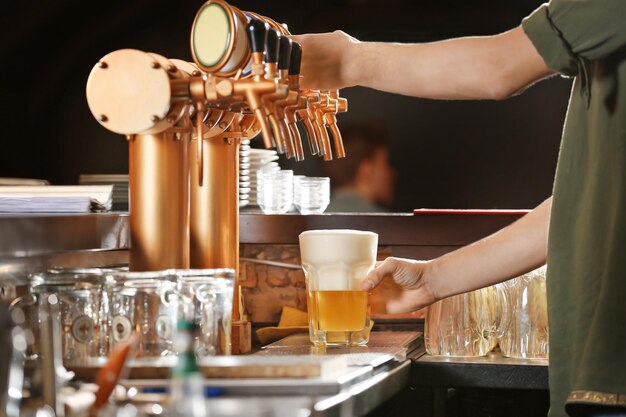 Foto barman manos vertiendo una cerveza lager en un vaso