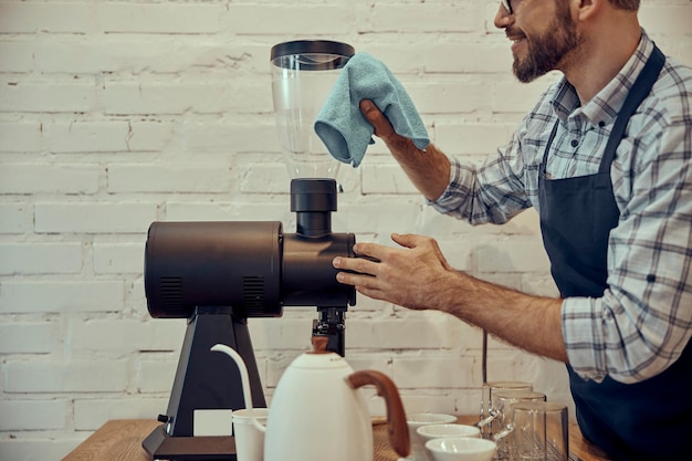 Barman masculino limpando a máquina de café no café