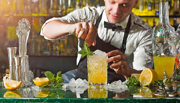 Barman mezclando un cóctel en las rocas con ingredientes naturales