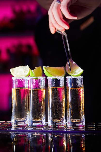 Barman poniendo cal en un vaso de tequila mexicano en el mostrador del bar