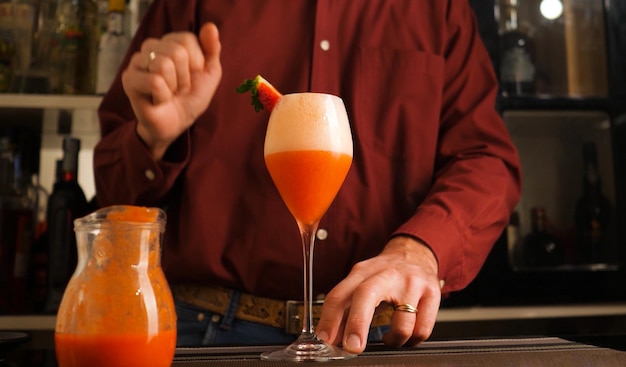 Barman prepara un cóctel italiano llamado Fragolino con jugo de fresa y vino espumoso
