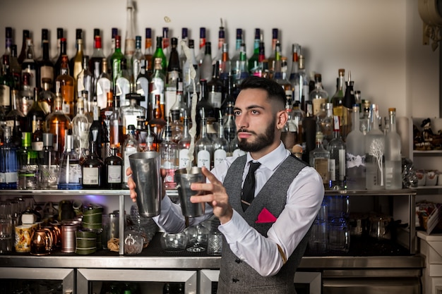 Barman profesional con agitador preparando bebida alcohólica