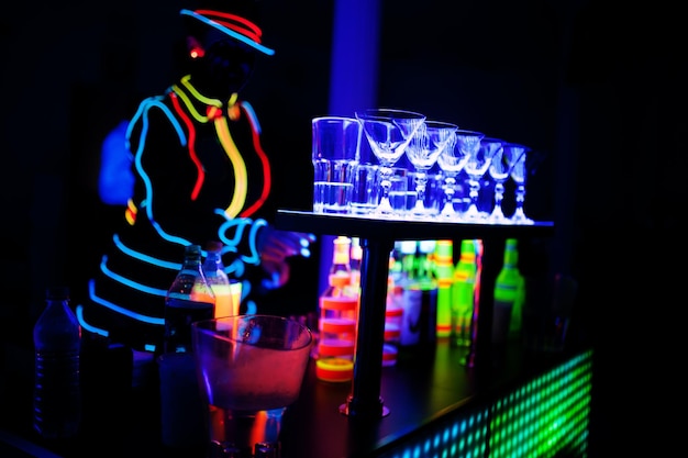 Barman profesional y espectáculo de luces led. Silueta de barman moderno sacudiendo bebida en el bar de cócteles nocturno.