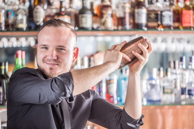 Barman profissional fazendo coquetel bebida shaker branco.