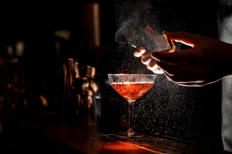 Foto barman pulveriza uma casca de laranja em copo de coquetel