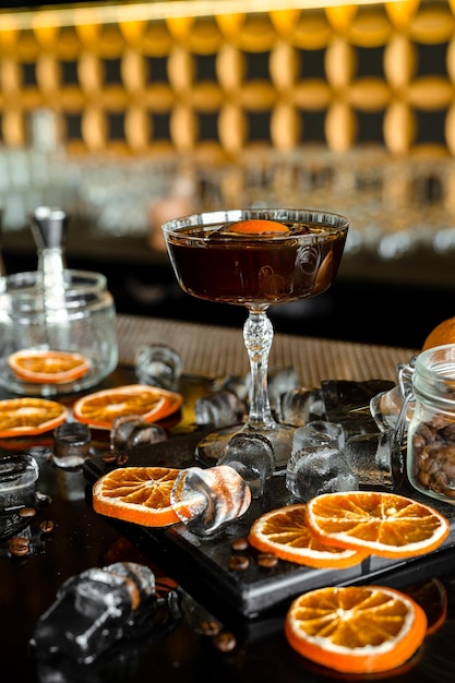 Barman realizando um coquetel de luxo vermelho fresco alcoólico no bar decorado com laranjas