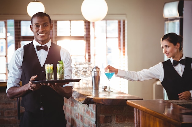 Barman, segurando uma bandeja com dois copo de cocktail