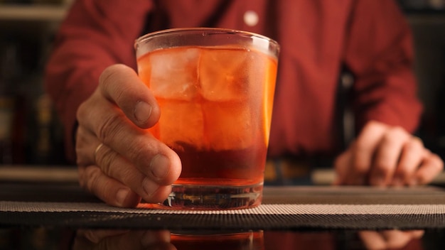 Barman serve um coquetel Negroni no balcão do bar