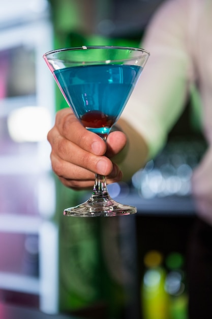 Barman, servindo um martini azul em bar