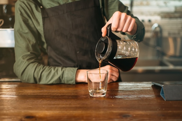 El barman sirve café en un vaso.