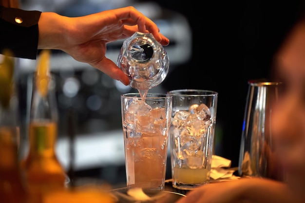 El barman sirve cócteles en la barra del bar Bokeh de fondo borroso