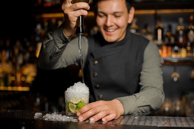 Barman sonriente que vierte jarabe dulce en el mojito