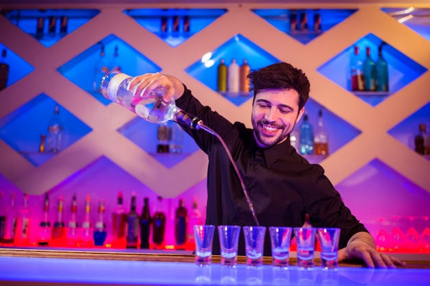 Barman, sorrindo, enquanto derramamento de álcool no copo