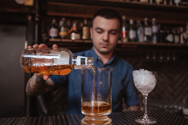 Barman tatuado masculino bonito, preparando uma bebida