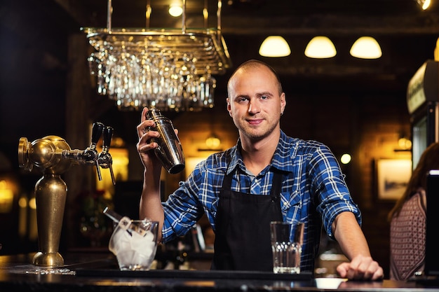 Barman en el trabajo vertiendo alcohol duro en vasos y preparando cócteles en detalle