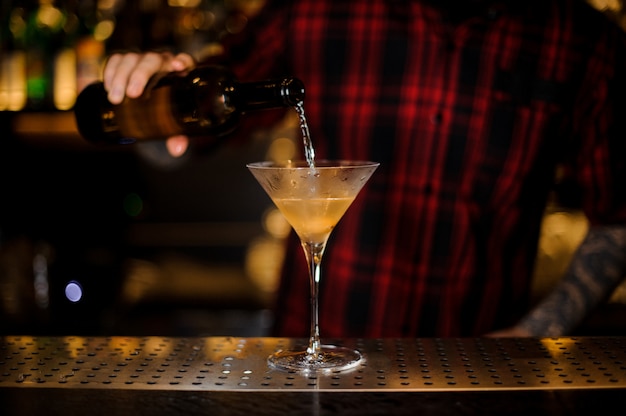 Barman vertiendo bebida en una elegante copa de cóctel