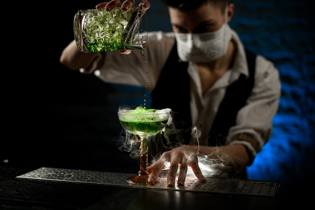 Barman vierte una bebida alcohólica verde fría en un vaso