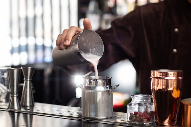 El barman vierte suavemente el cóctel terminado de la coctelera en el cuerpo de cristal metálico del barman