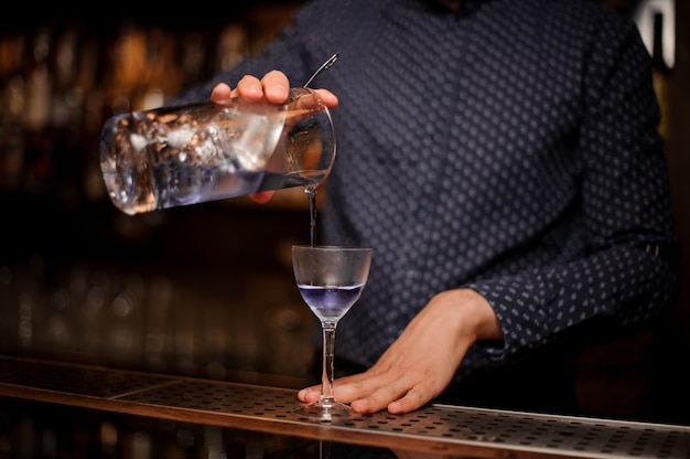 Barmann, der starkes und frisches Sommergetränk in das Cocktailglas gießt