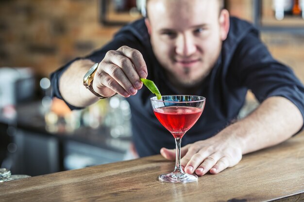 Barmann in der kneipe oder im restaurant, die ein cocktailgetränk zubereitet.