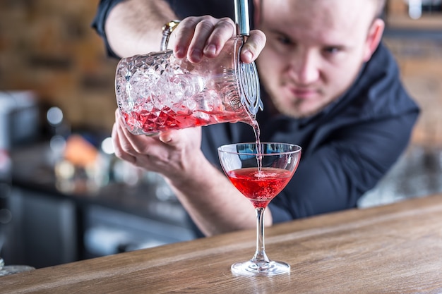 Barmann in der Kneipe oder im Restaurant, die ein Cocktailgetränk zubereitet.