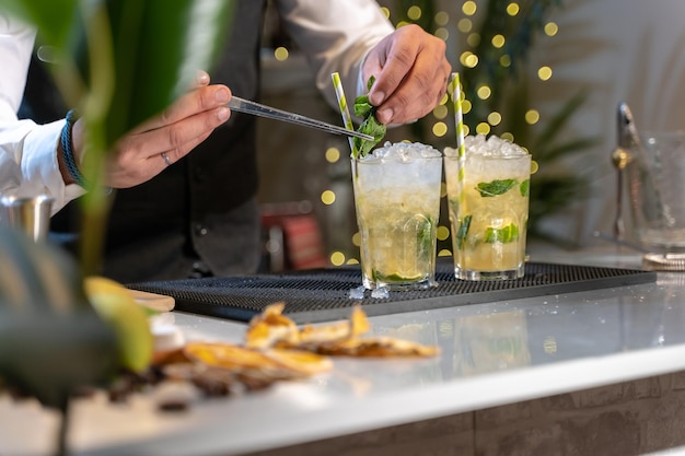 Barmann macht Cocktail Mojito im Nachtclub, fügt Zutaten hinzu und kreiert fachmännische Getränke an der Bartheke