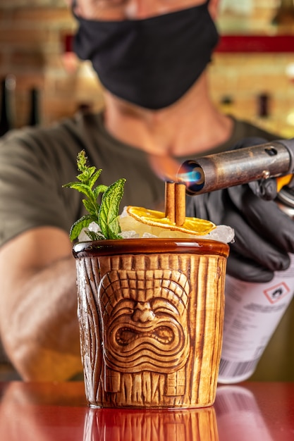 Barmann zündet Zimt im Tiki-Cocktail an der Bar an