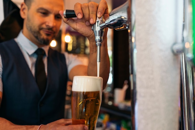 Barmannshand am Bierhahn, der ein gezapftes Lagerbier gießt, das in einer Kneipe dient