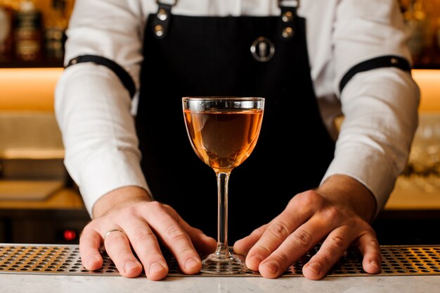 Barmans mãos segurando um copo com bebida alcoólica