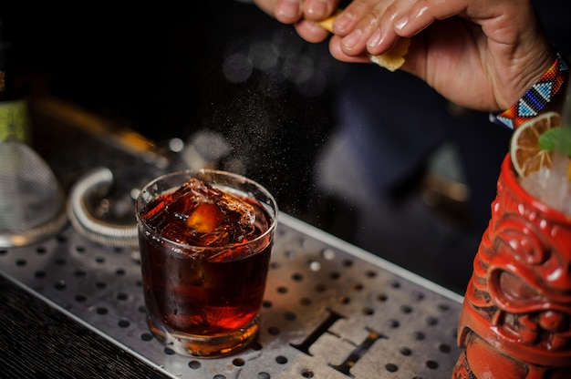 Barmixerhände, die Orangensaft in das Cocktailglas spritzen