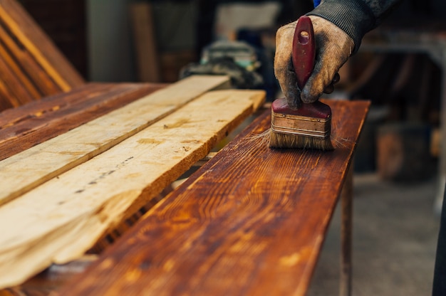 Barnizar un tablón de madera con pincel.