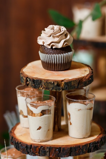 Barra de caramelo en banquete de boda de madera con una gran cantidad de diferentes dulces cupcakes soufflé y tortas