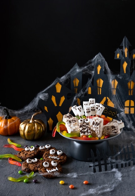 Barra de caramelo de Halloween monstruos divertidos hechos de galletas con chocolate y primer plano de malvavisco de fantasmas sobre la mesa. Decoración de fiesta de Halloween. Concepto de truco o trato.