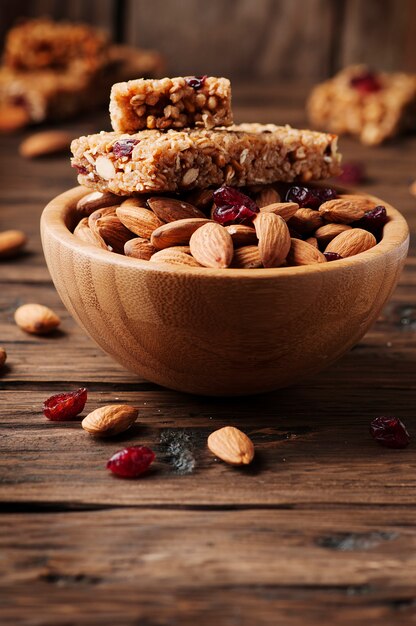 Barra de cereales con almendras y bayas en la mesa de madera