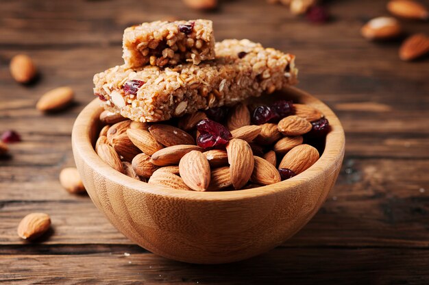 Barra de cereales con almendras y bayas en la mesa de madera