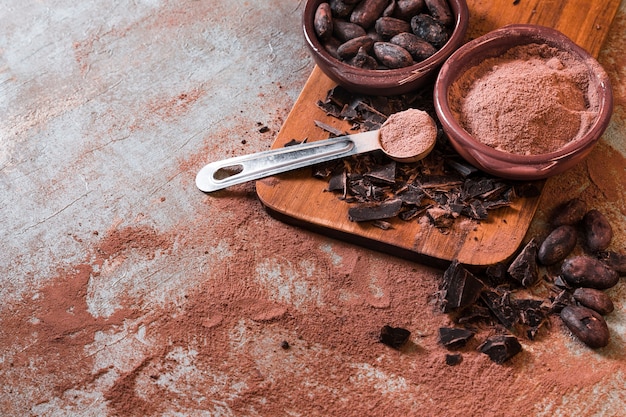 Foto barra de chocolate agrietado con cacao en polvo y frijoles