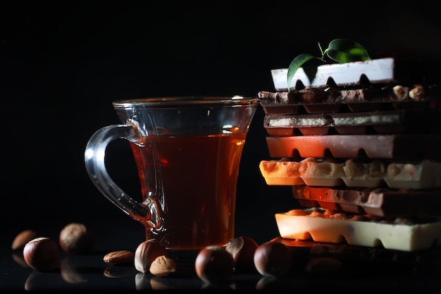 Una barra de chocolate con leche. Chocolate con leche casero con almendras y fresas secas. Trozos de chocolate con leche. Barra de chocolate con leche sin etiqueta. Juego de chocolate con té.