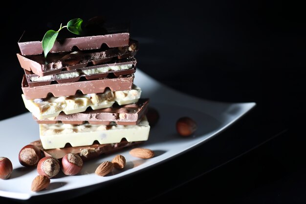 Una barra de chocolate con leche. Chocolate con leche casero con almendras y fresas secas. Trozos de chocolate con leche. Barra de chocolate con leche sin etiqueta. Juego de chocolate con té.