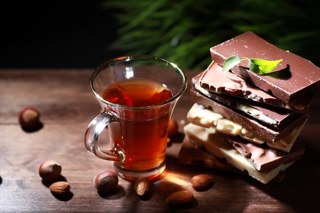 Una barra de chocolate con leche. Chocolate con leche casero con almendras y fresas secas. Trozos de chocolate con leche. Barra de chocolate con leche sin etiqueta. Juego de chocolate con té.